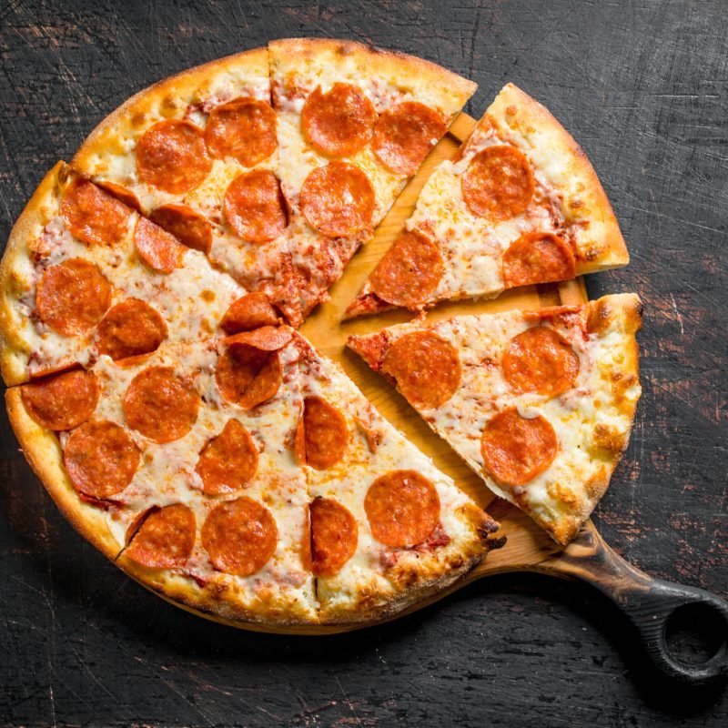 Crispy pepperoni pizza on the cutting Board. On dark rustic background